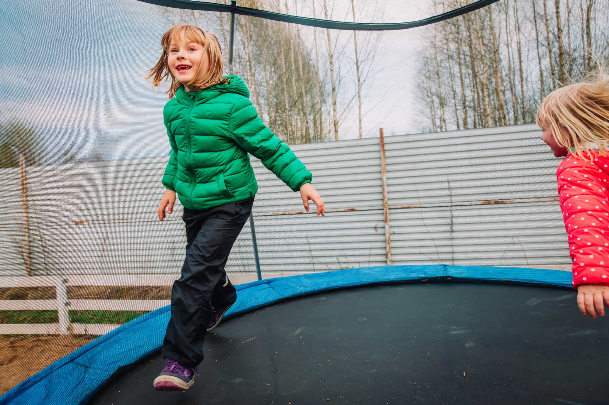 happy little girls enjoy jumping on trampoline - outside in backyard