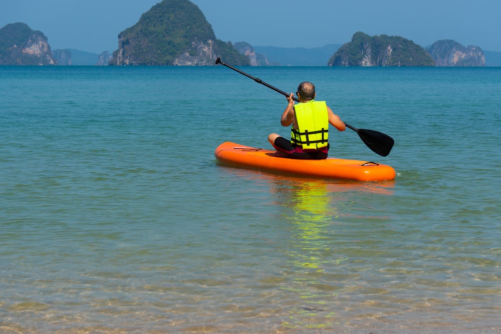 man with a life jacket on inflatable SUP